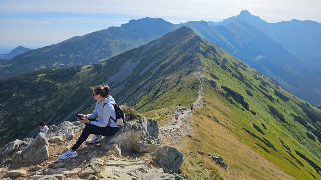 A woman hiking in the mountains sitting while taking a break